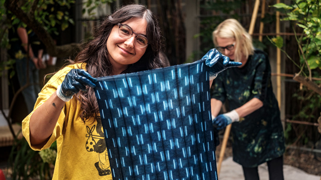 Person holding up a large fabric swatch of indigo dyeing