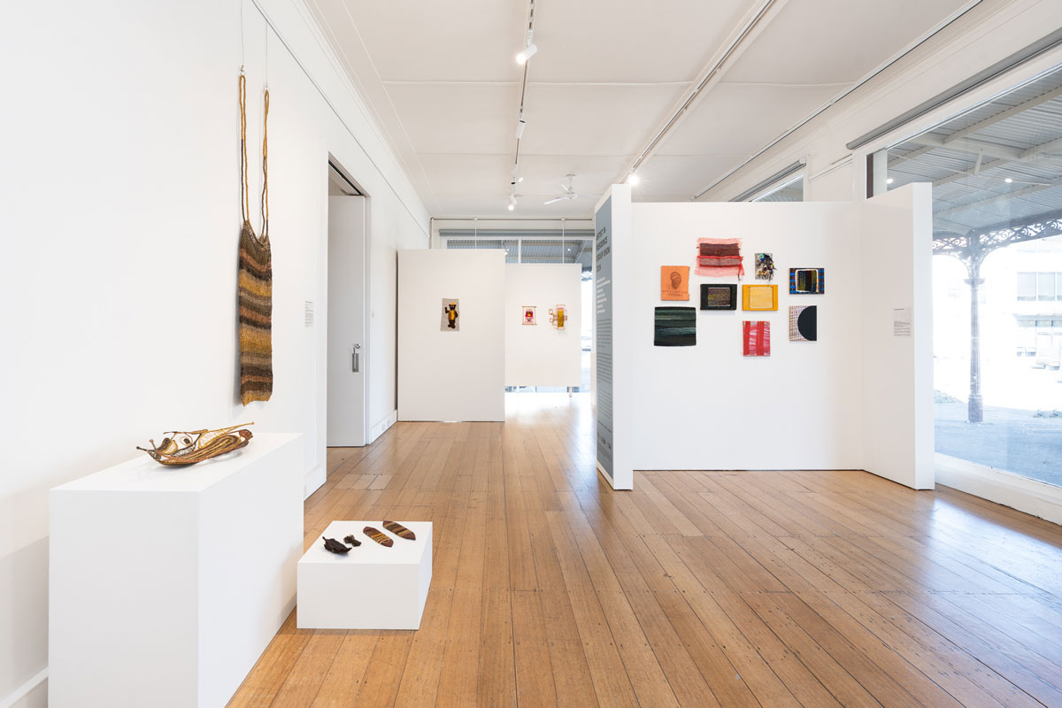 A bright gallery space full of textile artworks