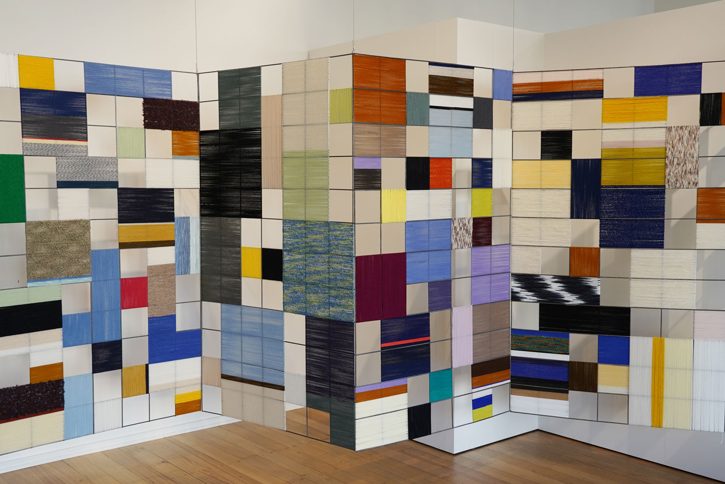 Jacqueline Stojanović, Concrete Fabric, 2019,
wool on industrial steel mesh, dimensions variable. Installation view of Jacqueline Stojanović's artwork featuring coloured yarn wound around wide metal mesh, forming a vibrant, grid-like structure.