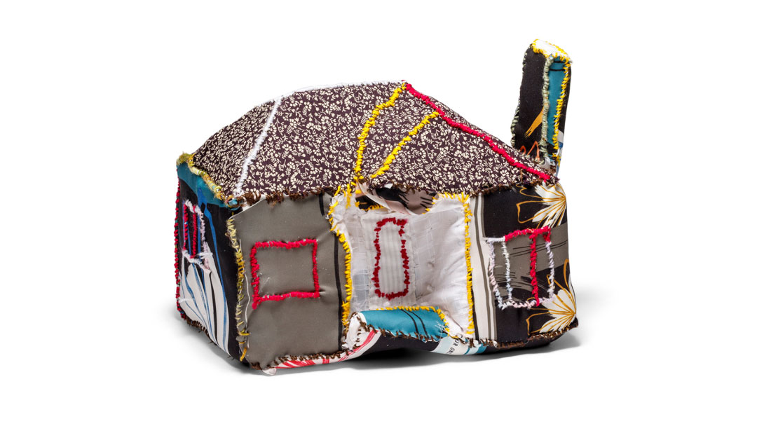 A soft, fabric house sculpture made from colorful patchwork textiles.