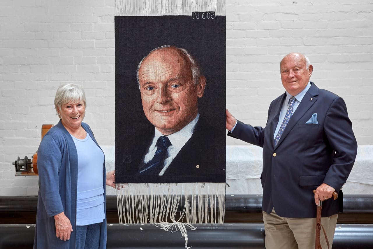 Lynn Rainbow-Reid AM and John B Reid AO with their commissioned tapestry, woven by Pamela Joyce at the ATW in 2019. Photo by Jeremy Weihrauch. 